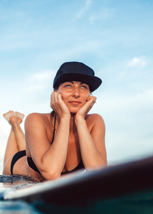 Girls on surfboard wearing hat in the ocean